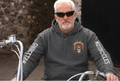 Man wearing a hoodie with a motorcycle design, sitting on a bike.