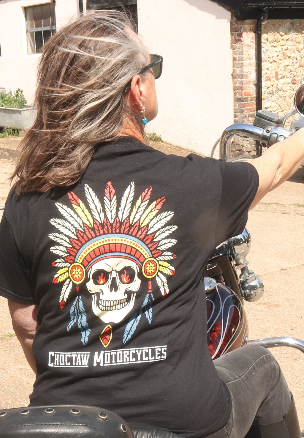 Person wearing a black t-shirt with a Choctaw Motorcycles design on a motorcycle.