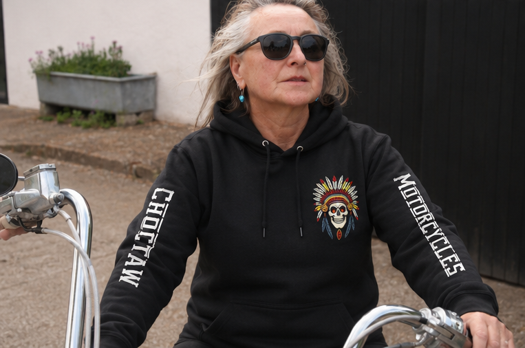 Person wearing a black hoodie with a skull design and text, sitting on a motorcycle.