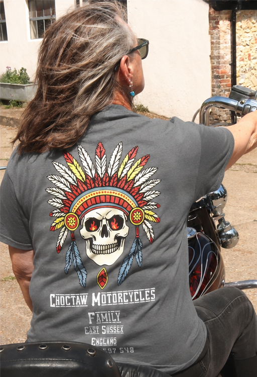 Person wearing a gray t-shirt with a Choctaw Motorcycles design, sitting on a motorcycle.